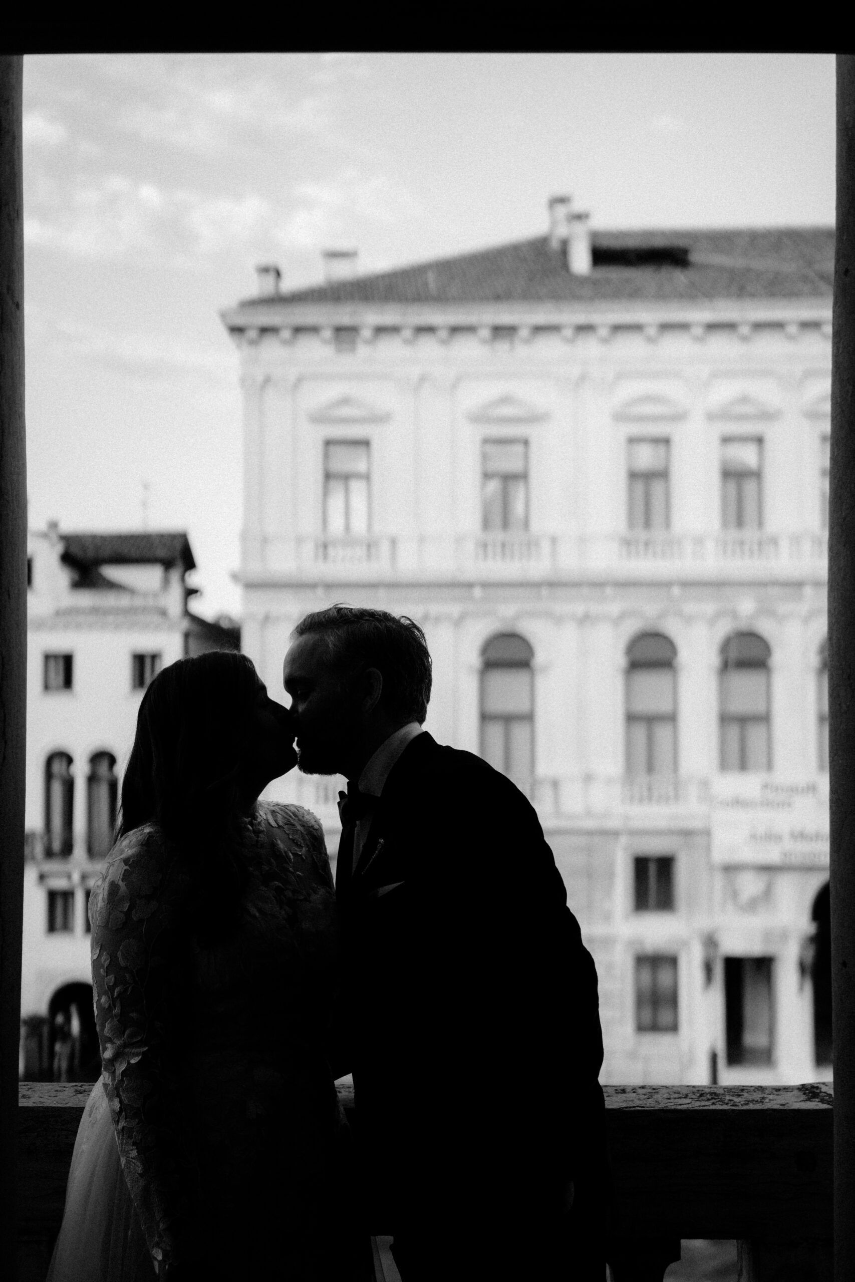 Novelli sposi che si baciano sul balcone con affaccio sul Canal Grande